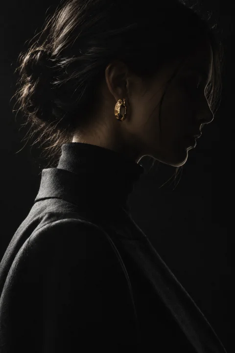 A profile half in shadow, a gold earring catching the light