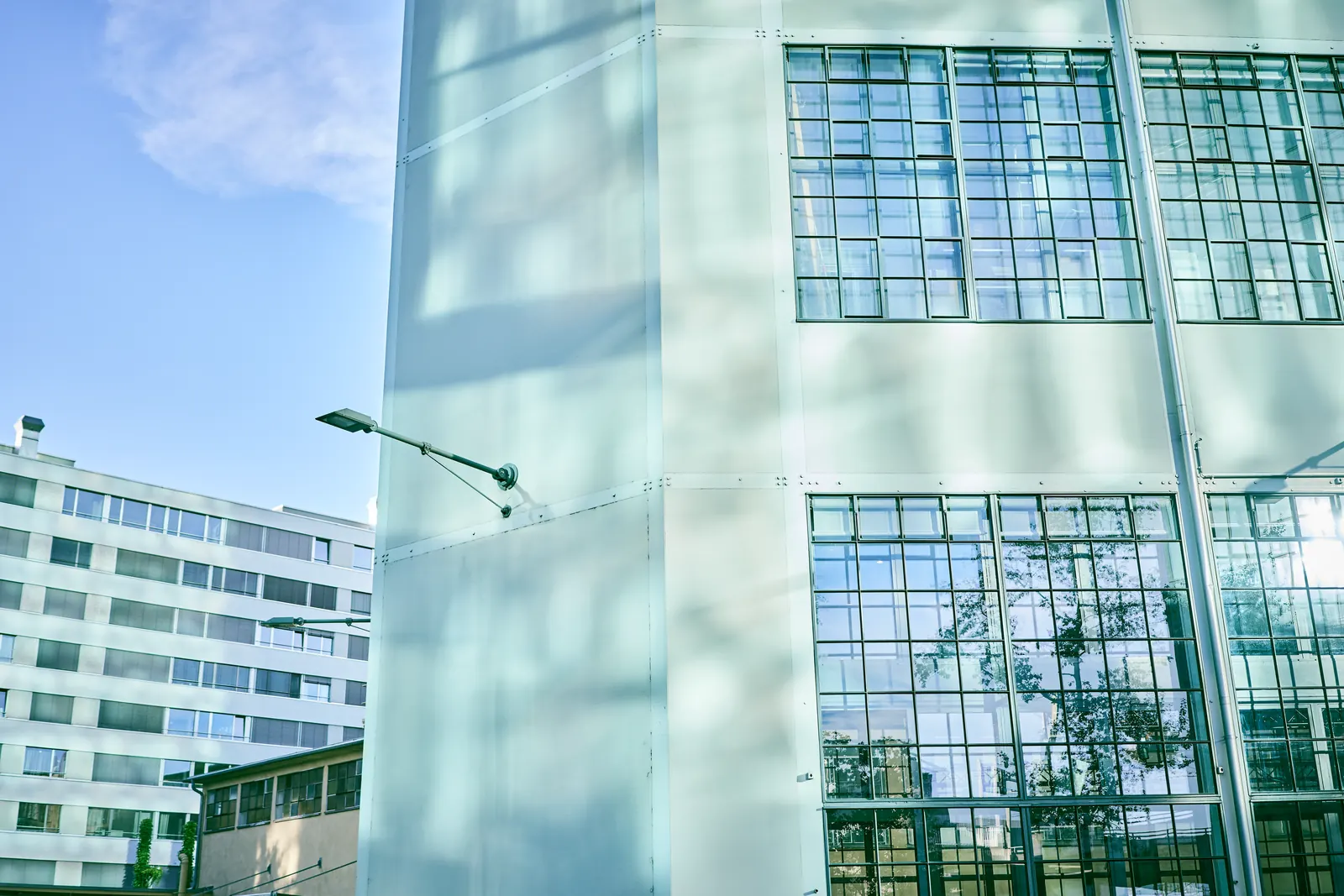 A frosted glass facade with steel-framed windows and a street lamp